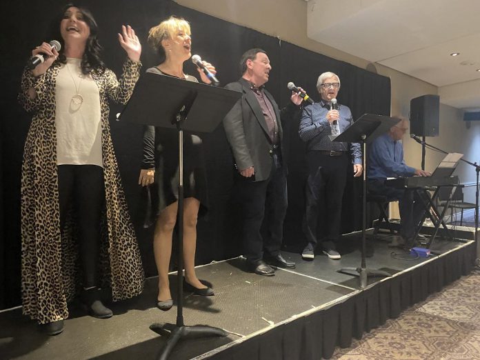 Along with the unveiling of a plaque honouring Showplace's founding chair Beth McMaster, the celebration on June 11, 2024 also featured entertainment in the Nexicom Studio from (left to right) Meg Murphy, Lisa Devan, Wayne Robinson, Bob Trennum, and Rob Phillips. Among the selections performed was a song written especially for McMaster. (Photo: Paul Rellinger / kawarthaNOW)