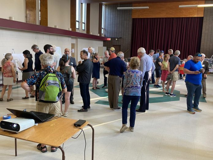 People gathered in the church hall at Mark Street United Church on June 20, 2024 for an open house for TVM Group's proposed 10-storey residential-commercial development on a property just west of the church. The mid-20th-century church hall would be demolished as part of the development, although the original church building would remain. (Photo: Paul Rellinger / kawarthaNOW)