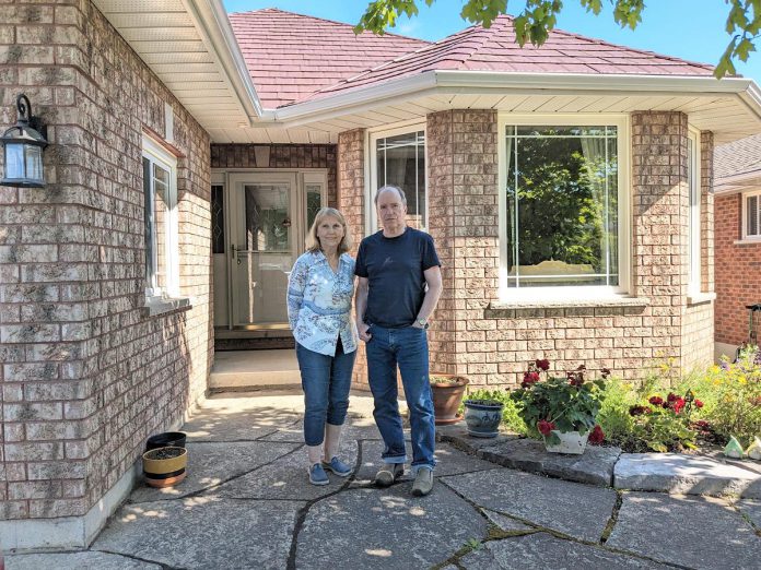 Norma and Michael Doran stand in front of their now fully electric Peterborough west-end home after having successfully completed a deep energy retrofit that allowed them to reduce their residential greenhouse gas emissions by over 86 per cent. (Photo: Clara Blakelock / GreenUP)