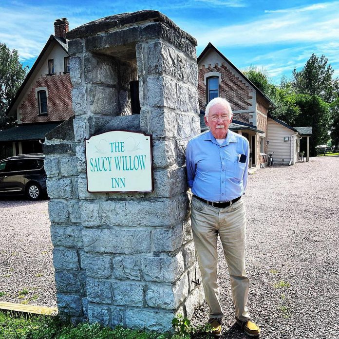 Ian Valentine from Sault Ste. Marie standing outside the Saucy Willow Inn & Cottages in 2022. Valentine was six years old when he helped break the ground for his father and uncle who built the pillars standing outside. In 2022, he was a guest at the inn and shared his stories and photos of the build.  (Photo courtesy of Saucy Willow Inn & Cottages)