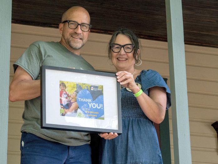 Bruce Hodges accepts a thank-you plaque from Allison Urowitz, vice-president of development and marketing of Ronald McDonald House Charities (RMHC) Toronto, during the fifth annual Wanakuen Concert which took place on July 13, 2024 at Bruce and Susan Hodges Stoney Lake property and raised almost $40,000 for RMHC Toronto. (Photo: Andrew Clowater)