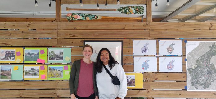 After a Living Cities visioning session that brought together diverse stakeholders, GreenUP program coordinator Laura Keresztesi (left) and board member Patricia Wilson pose with environmental equity maps and green infrastructure examples posted at the Silver Bean Café. (Photo: Tegan Moss / GreenUP)