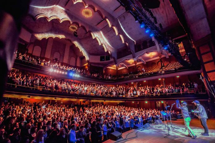 Nobu Adilman and Daveed Goldman of Choir! Choir! Choir! leading the audience at Toronto's Massey Hall. The pair will be at Peterborough Musicfest in Del Crary Park on August 14, 2024 for an epic sing-along of some of the biggest hits of the 1980s. (Photo: Joseph Fuda)