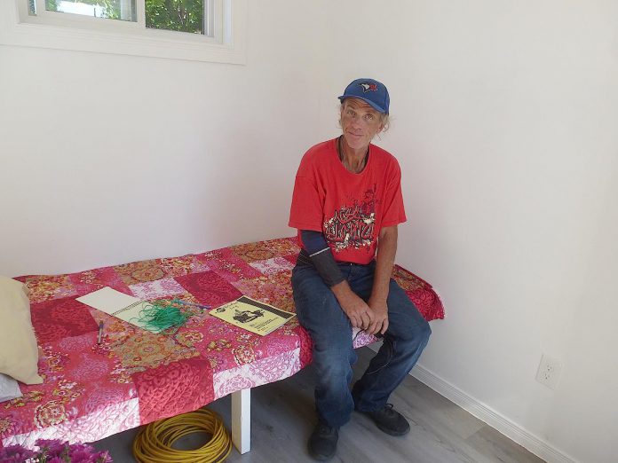 Terry, a Peterborough resident who supports himself by delivering papers and recycling bottles and cans, tries out the prototype sleeping cabin built by Peterborough Action for Tiny Homes (PATH). Having leased the site at 385 Lansdowne Street East for three years from Habitat for Humanity Peterborough and Kawartha Region, PATH is proceeding to Peterborough city council to obtain a temporary use zoning by-law amendment that would allow the organization to build 24 one-room sleeping cabins with wrap-around services to help address the city's homelessness crisis. (Photo: Peterborough Action for Tiny Homes)