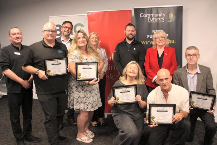 The graduates of Community Futures Peterborough's 2024 ScaleUP program, presented in partnership with Scotiabank, were celebrated during an event on September 17, 2024 at Venture North in downtown Peterborough. Pictured from left to right, front and back: Braden Clark of Community Futures Peterborough, Clint Clarke of Barking Pixel Design Co., Tracy Cosburn of Kyoto Coffee, Alicia Doris of Living Local Marketplace, Jacob Rodenburg of Camp Kawartha, Sean Flanagan of Flanagan and Sun, Peterborough city councillor Don Vassiliadis, Diane Richard of Diatom Consulting, Kevin Miller of Scotiabank, and Peterborough County warden Bonnie Clark. (Photo: Jeannine Taylor / kawarthaNOW)