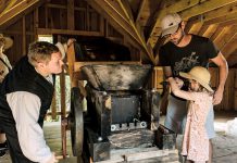 A young girl gets some help pressing apples for cider 19th-century style at the 2023 Applefest at Lang Pioneer Village Museum in Keene. The popular annual family event returns for 2024 on Sunday, October 7. (Photo: Heather Doughty Photography)