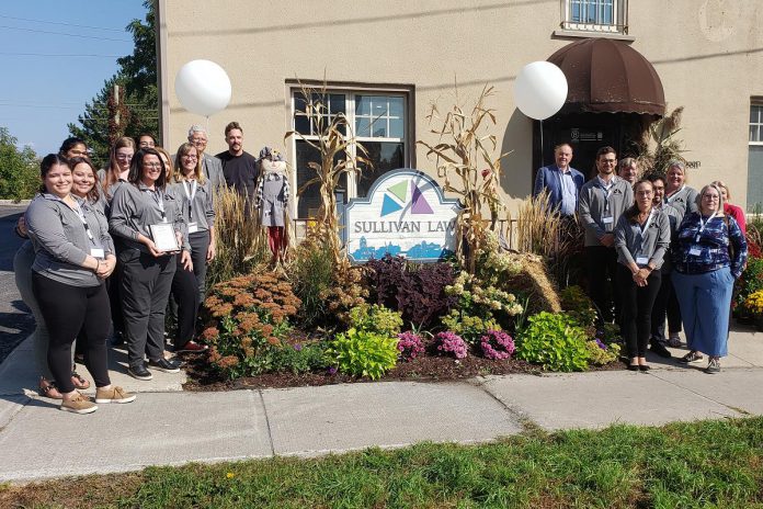 Martha Sullivan of Sullivan Law Ptbo (front, third from left) displays the law firm's B Corporation certification during a celebration on September 19, 2024 with staff and invited guests gathered the business's new office at 362 Queen Street in downtown Peterborough. (Photo: Jeannine Taylor / kawarthaNOW)