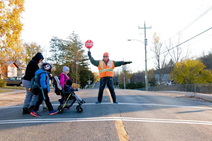 Crossing guards helps kids and families walk safely to school, such as this family crossing near Armour Heights in Peterborough. When kids learn the rules of the road at an early age, they are not just becoming safer pedestrians, but also laying the foundation to become responsible cyclists and potential future motorists. (Photo: Peter Rellinger)