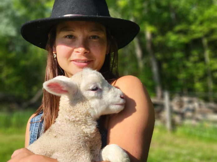 Beatrice Chan, the new program coordinator of the Net Zero Farms program, with one of her lambs from her farm in Selwyn Township where she farms sheep, cut flowers, meat chickens, and runs a flock of layers as well. She is looking forward to working with other local farmers in her new role as coordinator. (Photo: Bea Chan)