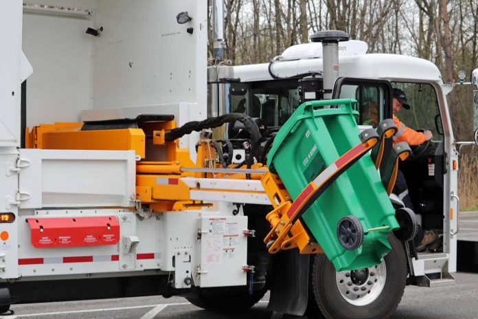 The city's fleet of split-body side-loading trucks, equipped with the helping-hand automated lift arm, empty organic waste from green bins at the curb into one compartment, with non-organic garbage collected in a separate compartment. (Photo: City of Peterborough)