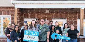 Through Habitat for Humanity Peterborough & Kawartha Region (Habitat PKR), 12 families (including Derrick and his daughter Maelyn, holding the sold sign) have achieved affordable homeownership of units at 21 Leahy's Lane in Peterborough. The non-profit organization held a dedication ceremony on October 20, 2024, that was attended by the families, dignitaries, project partners, and supporters. (Photo courtesy of Habitat PKR)