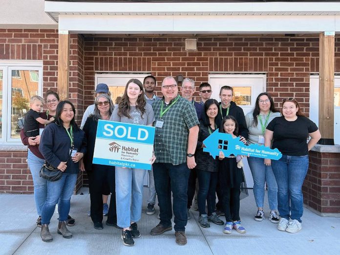 Through Habitat for Humanity Peterborough & Kawartha Region (Habitat PKR), 12 families (including Derrick and his daughter Maelyn, holding the sold sign) have achieved affordable homeownership of units at 21 Leahy's Lane in Peterborough. The non-profit organization held a dedication ceremony on October 20, 2024, that was attended by the families, dignitaries, project partners, and supporters. (Photo courtesy of Habitat PKR)