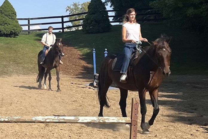 For their roles in "Mary's Wedding," actors Edward Sweeney and Justine Christensen need to create the illusion of riding a horse on the Peterborough Theatre Guild's stage. They did some hands-on research at Kendall Hills Equine to prepare for the equestrian part of their roles. (Photo: Peterborough Theatre Guild)