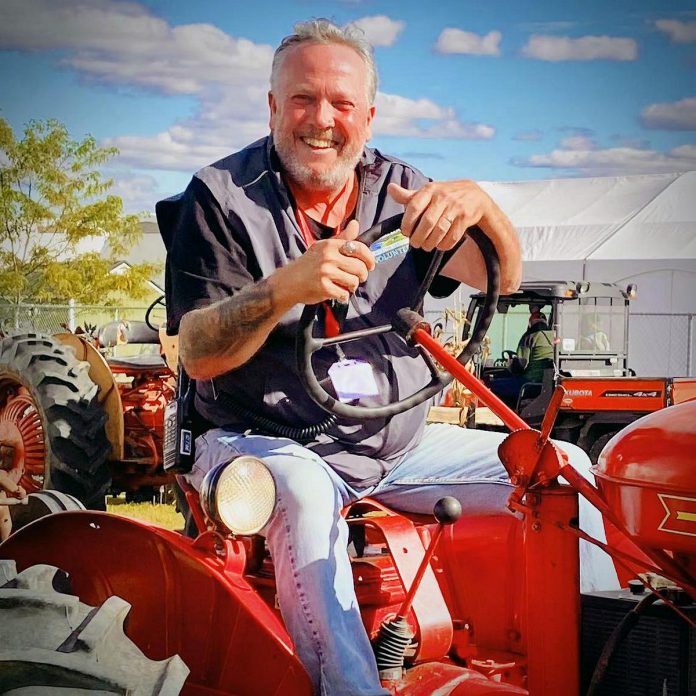 Lindsay & District Chamber of Commerce executive director Terry Guiel tries out a tractor during the International Plowing Match and Rural Expo at the Lindsay Fairgrounds from October 1 to 5, 2024, where he volunteered as entertainment coordinator and helped secure around 30 acts for the event that generates $25 million each year in the community where it is held. For 2025, Guiel says he is planning "a major festival" that " is going to be put Lindsay and area on the map." (Photo courtesy of Terry Guiel)