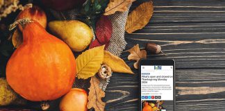 A mobile phone sitting on a harvest table covered with squash and fall leaves displaying kawarthaNOW's Thanksgiving Monday 2024 holiday hours story. (kawarthaNOW photo)