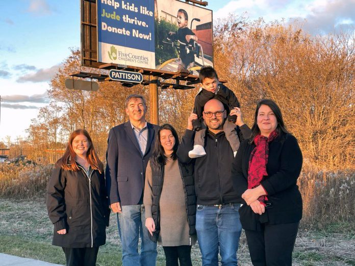 Five Counties Children's Centre staff members Maddie Jackson (far left) and Lyn Giles (far right) with Peterborough-Kawartha MPP Dave Smith (second from left) and Julie and Aaron Grant (holding his son Jude) in front of an outdoor billboard sign encouraging support for the children’s treatment centre. In 2023, Five Counties received a $135,200 grant from the provincial government’s Ontario Trillium Foundation to implement new fundraising and communications strategies. (Photo courtesy of Five Counties Children's Centre)