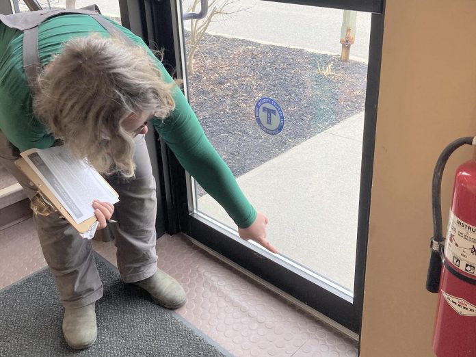 Addressing airtightness in your commercial building can be a low-cost place to start improving energy efficiency. Clara Blakelock, a registered energy advisor with GreenUP, points out a gap at the bottom of an exterior door. Adding a doorsweep to the door will mitigate energy loss. (Photo: Jackie Donaldson)