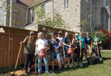 Volunteers in front of a row of birch and black cherry trees along the fence at Trinity Community Centre in Peterborough on September 10, 2024. GreenUP, along with Trinity Community Centre guests and One City Peterborough staff, devised a planting plan to manage storm water, increase food security, and create shade. It was one of several projects that led to the planting of more than 1,500 trees this year in Peterborough. (Photo: Laura Keresztesi / GreenUP)