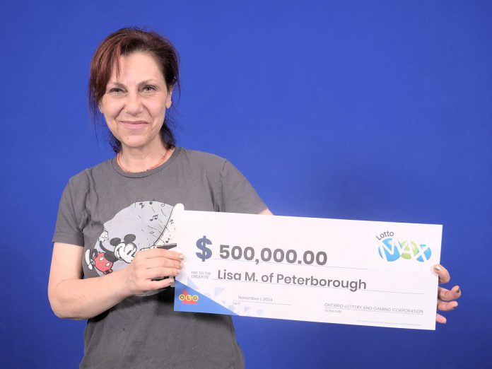 Peterborough artist Lisa Martini-Dunk with her $500,000 in winnings from the Lotto Max draw on October 15, 2024. She purchased her winning ticket online. (Photo: OLG)