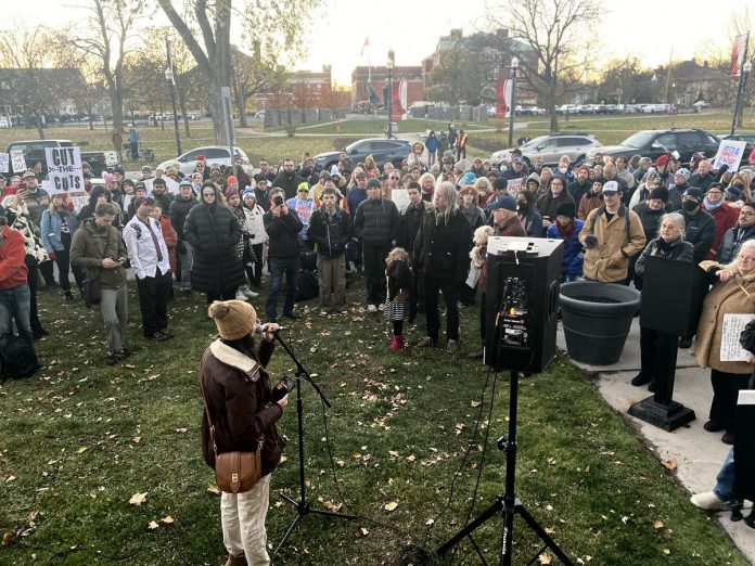 A speaker addresses the crowd outside Peterborough City Hall on November 12, 2024 to protest a proposed 25 per cent across-the-board cut in the City of Peterborough's 2025 draft budget to grants to community organizations. (Photo: Paul Rellinger / kawarthaNOW)