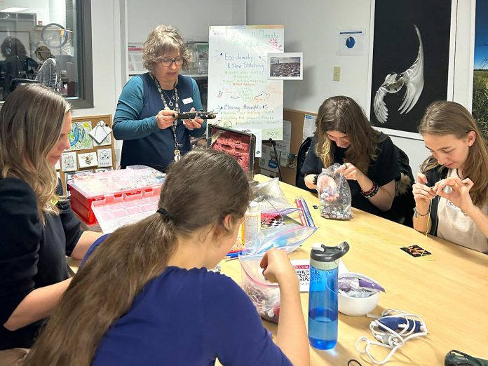 Guest artist Lisa Noble from the Trent University School of Education leads GreenUP Youth Climate Action participants in a workshop activity to create jewellery with recycled parts like bike chains and buttons. The workshop held on November 14, 2024 empowered youth to creatively keep used items out of landfills. Youth who complete four of the six workshops in the series receive a certificate adding a valuable credential to their resume. (Photo: Angela Sundue)