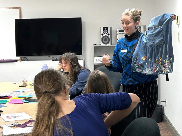 Brianna VanEsch, local artist and Trent University teacher candidate, helps youth learn fabric renewal with slow stitching to repurpose fabric scraps into creative new designs during a workshop held on November 14, 2024. Combatting fast fashion was identified as a theme to focus on during an initial brainstorming session where young participants co-designed the Youth Climate Action workshop series. (Photo: Megan Allen)