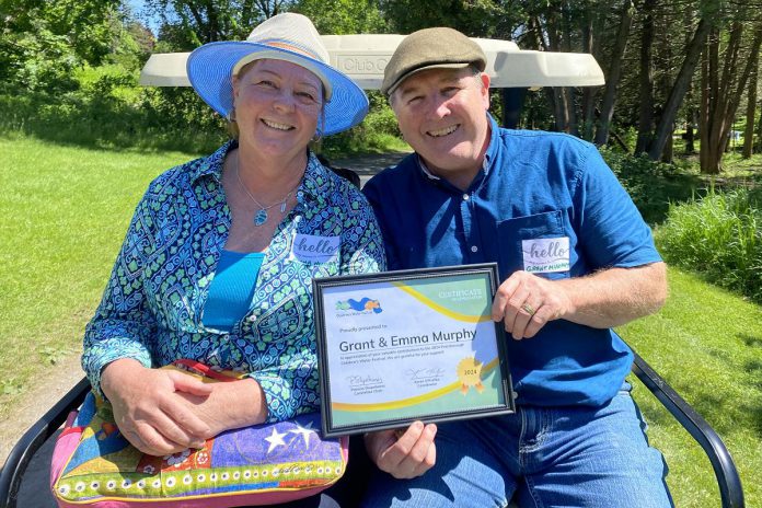 Longtime donors Grant and Emma Murphy pose on a golf cart with a certificate of appreciation during the 2024 Peterborough Children's Water Festival. Individual and corporate donors, as well as event sponsors, are critical to this beloved community event. (Photo: Natalie Stephenson / GreenUP)