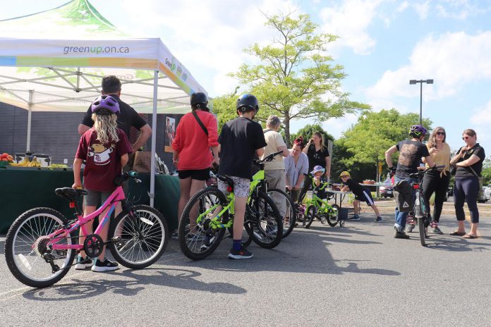 Kids and families get a helmet fit and bike check-ups at GreenUP's Let's Bike event on July 12, 2024. The community event invites children and their families to learn about bike equipment, safety, handling skills and more through an outdoor fair. Through its active transportation programs, GreenUP encourages people to consider alternatives to driving cars, including walking, cycling, and taking public transit. (Photo courtesy of GreenUP)