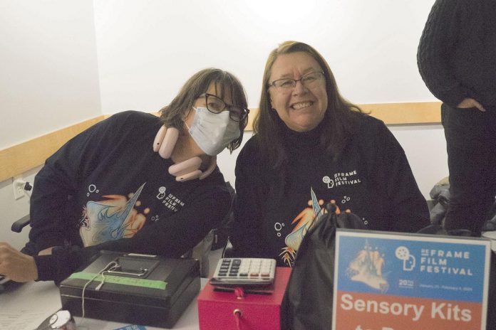 Volunteers Kat Tannock and Moray Post collect tickets during the 2024 ReFrame Film Festival. The festival is still seeking volunteers for the in-person portion of the 2025 festival, which takes place from January 23 to 26, 2025 in downtown Nogojiwanong/Peterborough. Flexible volunteer positions include audience services like running the box office, merchandising, ushering, and providing technical support. (Photo: Esther Vincent, courtesy of ReFrame Film Festival)