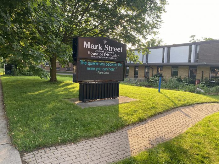 Pictured in June 2024, the site of TVM Group's proposed 10-storey residential-commercial development, which would be located immediately west of the Mark Street United Church building at 90 Hunter Street East in Peterborough's East City. The church sold the property, including attachments to the original church building (pictured in the background and since demolished), in exchange for four units in TVM Group's nearby East City Condos development and the construction of a new church hall. (Photo: Paul Rellinger / kawarthaNOW)