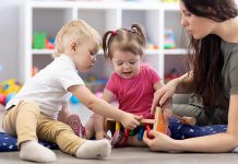 Two young children and an early childhood educator. (Stock photo)