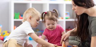 Two young children and an early childhood educator. (Stock photo)