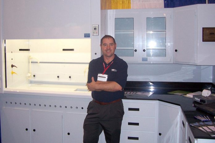 GreenUp executive director Tegan Moss's father Ric Moss, pictured with a display of custom fabricated laboratory equipment he built while working for TFI Inline circa 1998, earned his living and supported his family as a plastic fabricator. (Photo courtesy of Tegan Moss)