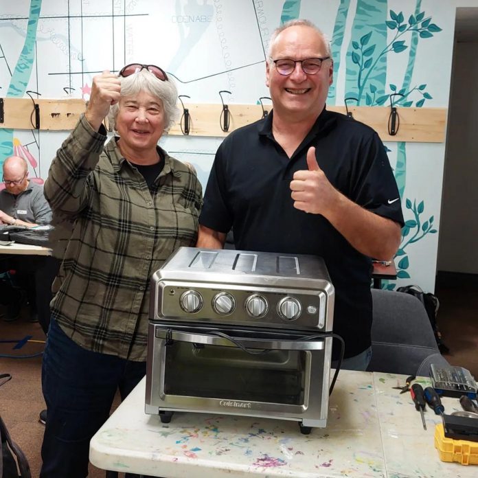 A volunteer and a community member celebrate as they complete a difficult repair on a toaster oven during a Repair Café event at GreenUP on November 19, 2024. Repairing items to extend their useful life is one of many ways to take part in a circular economy. (Photo courtesy of Repair Café Peterborough)