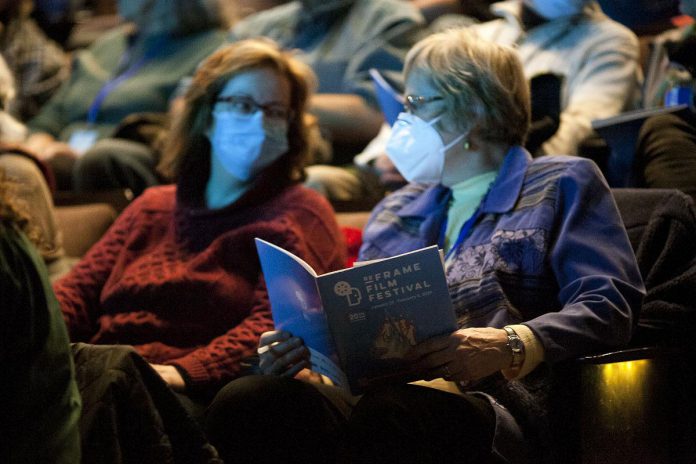 Two audience members wearing masks at the 2024 ReFrame Film Festival. Given that social justice is at the core of the ReFrame Film Festival, the festival's staff and board ensures it continues to meet the needs of the community by striving to deliver a festival that is physically, emotionally, and economically accessible as much as possible. The 2025 festival will feature more than 50 documentary films in downtown Nogojiwanong/Peterborough from January 23 to 26 and virtually from January 27 to February 2. (Photo: Esther Vincent, courtesy of ReFrame Film Festival)