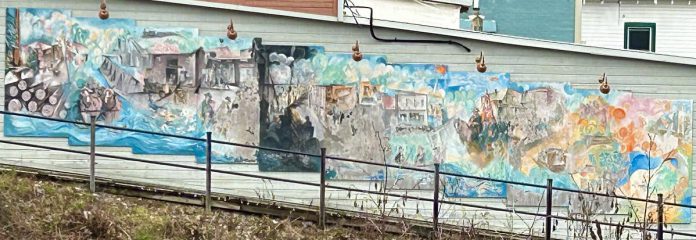 In 2014, renowned local artist Arne Roosman painted an 11-panel, 44-foot mural on the western side of the building at 23 Bridge Street in Bancroft. With his permission, A Place for the Arts is calling on regional professional and hobbyist artists to help revitalize the mural throughout July and August. (Photo courtesy of A Place for the Arts)