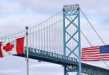 Canadian and American flags fly near the Ambassador Bridge connecting Canada to the U.S. in Windsor, Ontario. (Photo: Rod Gurdebeke / The Canadian Press)