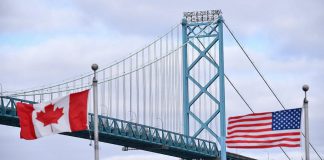 Canadian and American flags fly near the Ambassador Bridge connecting Canada to the U.S. in Windsor, Ontario. (Photo: Rod Gurdebeke / The Canadian Press)