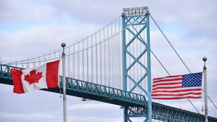 Canadian and American flags fly near the Ambassador Bridge connecting Canada to the U.S. in Windsor, Ontario. (Photo: Rod Gurdebeke / The Canadian Press)