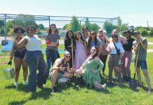 An enthusiastic group from Community Race Relations Committee of Peterborough's Resilient Roots program join volunteers from the Peterborough Community Orchard Stewards for stewardship day on May 29, 2024 at the community orchard at Keith Wightman Park in Peterborough. The group helped to water and feed the trees, spread new mulch rings around the bases, and plant raspberry canes. (Photo: Laura Keresztesi / GreenUP)