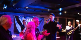 Peterborough Musicians Benevolent Association (PMBA) board members look on as pianist Rob Phillips announces a donation of $50,000 from supporter Lynn Morris at the February 15, 2025 PMBA blues jam at The Social in downtown Peterborough. Morris died two days later after a lengthy battle with cancer. (Photo: Andy Carroll)