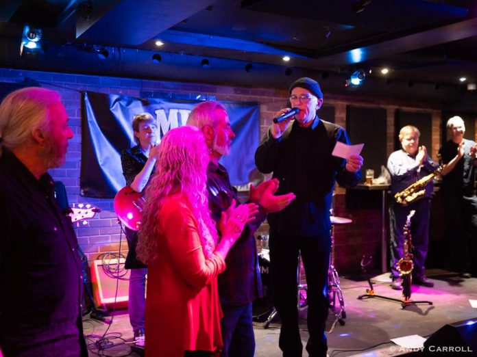 Peterborough Musicians Benevolent Association (PMBA) board members look on as pianist Rob Phillips announces a donation of $50,000 from supporter Lynn Morris at the February 15, 2025 PMBA blues jam at The Social in downtown Peterborough. Morris died two days later after a lengthy battle with cancer. (Photo: Andy Carroll)