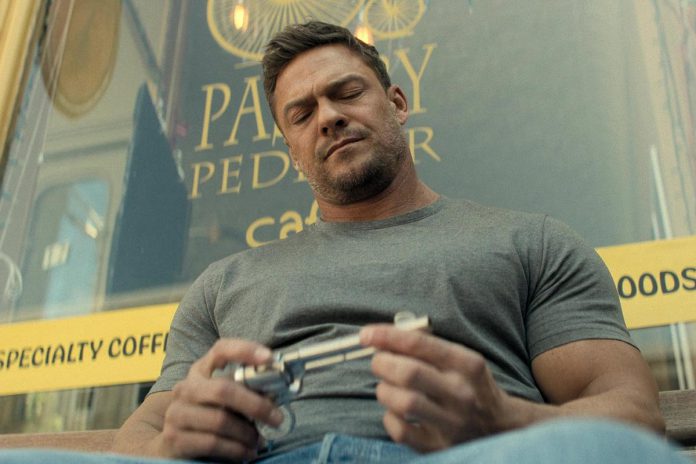 Jack Reacher (Alan Ritchson) sits on a bench in front of Pastry Peddler in downtown Millbrook in a scene from the third episode of the third season of the action-thriller series "Reacher" streaming now on Amazon Prime Video. (kawarthaNOW screenshot)