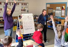 Five Counties clinicians Katy Morton (left) and Emily Vann get first and second graders at St. Joseph's Catholic Elementary School in Douro to stretch and show how "tallies" (letters like t, f, and b) differ from others in the alphabet. The exercise aims to reinforce proper printing techniques for the students. (Photo courtesy of Five Counties)