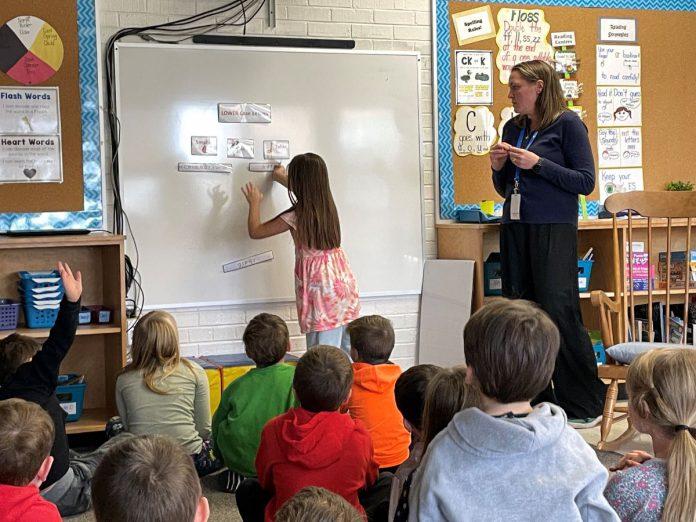 As Five Counties clinician Emily Vann looks on, a St. Joseph's student successfully applies a sticker showing that the letters like b, d, and f are "tallies" and not to be mistaken for "smallies" letters like a, c, and e or "sinkers" letters like g, j and y. School-based rehab services are a big part of the work Five Counties staff do to support kids and families in the community. (Photo courtesy of Five Counties)