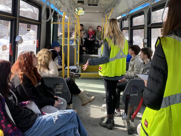 Grade 8 students from Queen Mary Public School learn about the many benefits of using transit during a Grade 8 Transit Quest orientation workshop held on a Peterborough Transit bus that was deployed to local schools. The orientation covers topics including boarding the bus, accessibility features, route planning, using a transfer, rider etiquette, safety, and more. (Photo: Natalie Stephenson / GreenUP)