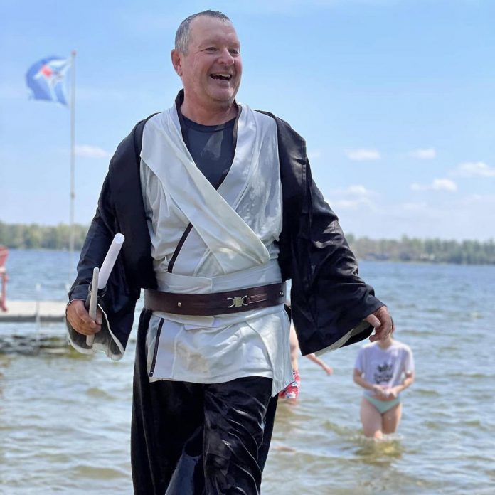 Local real estate sales representive Dean Michel emerges from Balsam Lake on May 4, 2024 during the Jump in the Lake Challenge, which had a Star Wars theme. During the pandemic lockdowns in April 2020, Michel decided to jump off his dock into the lake to raise money for the Coboconk & Area Food Bank, convincing his wife Jennifer Bacon to join him. The initiative inspired neighbours to also take the plunge, and the event has since turned into an annual community celebration to mark the arrival of spring while raising more than $175,000 for the community. (Photo courtesy of Dean Michel)