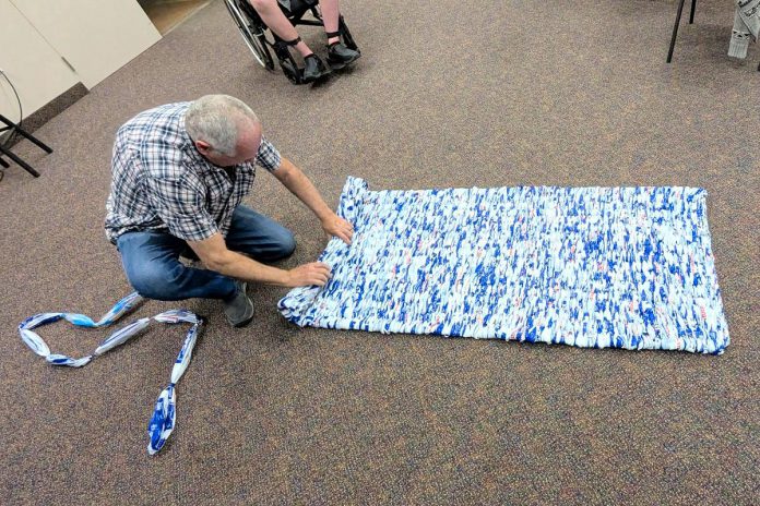 Using a custom-made loom, it takes approximately 500 milk bags for volunteers of Peterborough's Calvary Pentecostal Church to make one sleeping mat which is distributed to local unhoused individuals by the Street Level Advocacy organization. The sleeping mats are 33" x 78", thin, cushioned, and water resistant, and can be rolled up for easy transport. (Photo: Steve Paul / LinkedIn)