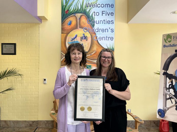 Five Counties Children's Centre clinical services director Darlene Callan and executive assistant Brandi Williamson-Meletiou display the three-year accreditation plaque from the Commission on Accreditation of Rehabilitation Facilities (CARF). In 1985, Five Counties was the very first children's treatment centre in Ontario to be accredited by the independent non-profit accreditor of health and human resources, and it has maintained its accreditation ever since. (Photo: Five Counties Children's Centre) Five Counties Children's Centre clinical services director Darlene Callan and executive assistant Brandi Williamson-Meletiou display the three-year accreditation plaque from the Commission on Accreditation of Rehabilitation Facilities (CARF). In 1985, Five Counties was the very first children's treatment centre in Ontario to be accredited by the independent non-profit accreditor of health and human resources, and it has maintained its accreditation ever since. (Photo: Five Counties Children's Centre)
