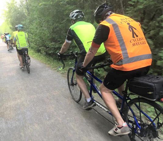 Between the lone line of tandem bicycles and the bright colours, a TandemEyes group ride is hard to miss on a summer evening. Here, the group passes through Jackson Park in Peterborough on the way to the Orange Corners trestle bridge. (Photo courtesy of TandemEyes)